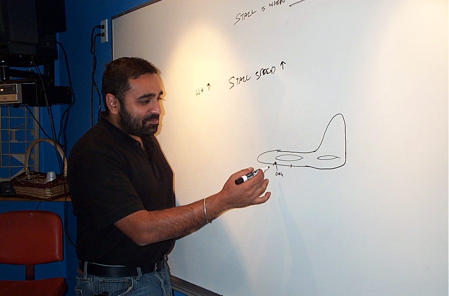 Flight Instructor Gobind Sandhanwalia demonstrates his deptiction of an aeroplane for the purpose of theoretical conjecture.  Langley Flying School.