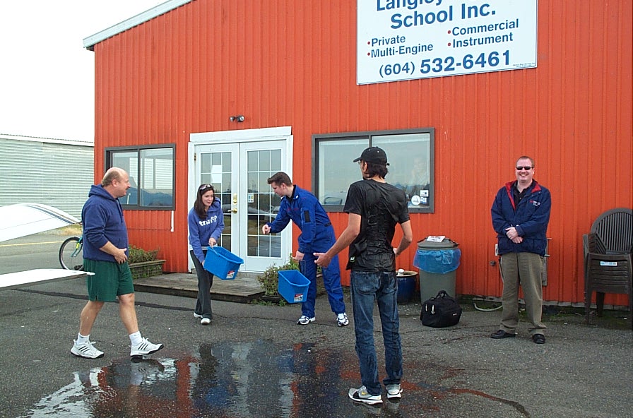 During congratulatory hand-shake picture with Dave Parry and Peter Cox, Instructor Naomi Jones and Phil Craig sneek up behind Mayank with two buckets of water--and it wasn't warm water. Langley Flying School.